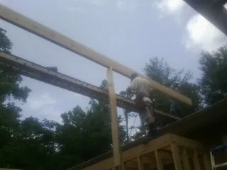 Carpenter setting a ridge beam over a new addition frame — Ice Dam Removal by Roofing Brothers in Delta City