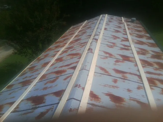 Rusted metal roof panels with new wood purlins before replacement — Storm Damage Roof Repair in Delta City by Roofing Brothers