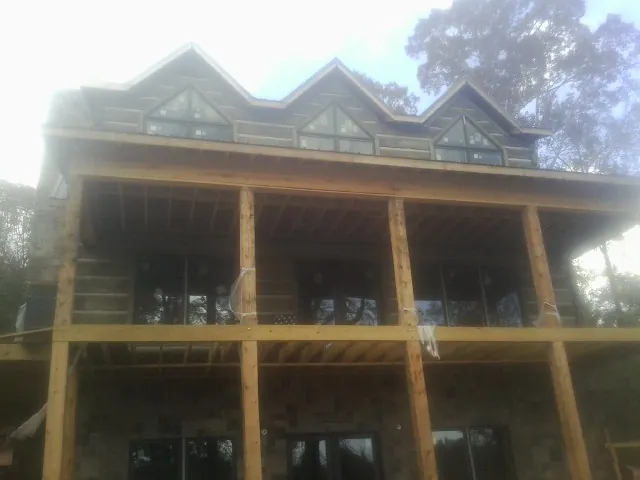 Dormers and porch framing on a large log home under construction — Roof Coating work by our crew in Delta City