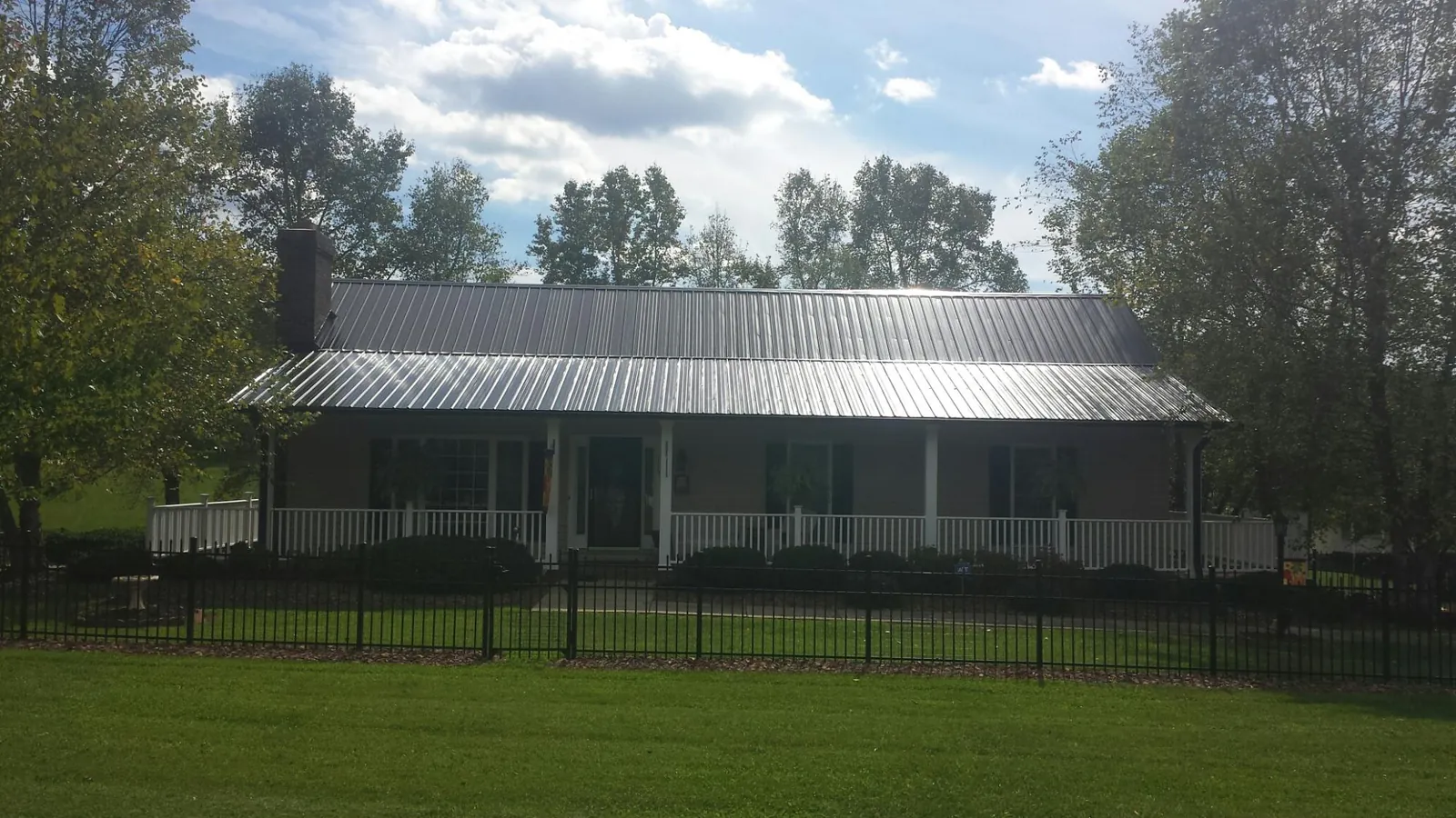 Gray metal roof on a brick ranch with a full width front porch — Gutter Guard Installation work by our crew in Delta City