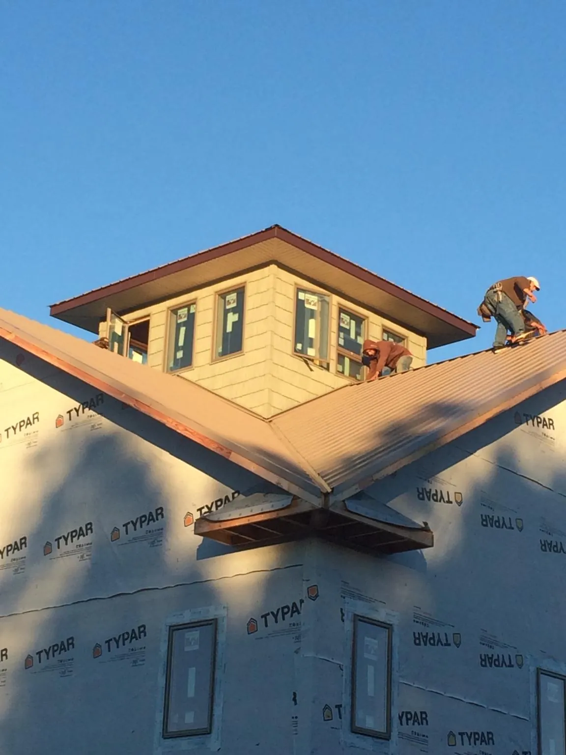 Roofers working around a rooftop cupola on a new metal roof at sunset — Roof Waterproofing in Delta City by Roofing Brothers